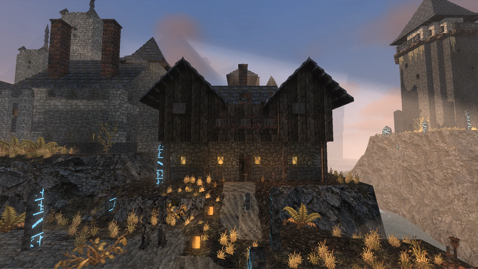 The Sunken Lantern inn on its rock at dusk, lit windows below the old town